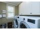 Bright laundry room featuring white cabinets, a sink, and modern washer and dryer appliances at 4953 Mashpee Ln, Apex, NC 27539