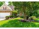 Beautifully landscaped front yard with mature trees, lush green lawn, and stone accents at 509 Fish Pond Ct, Rolesville, NC 27571