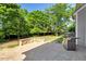Backyard featuring a stone patio, built-in stone bench, gas grill and manicured grass and trees at 5404 Onyx Mill Ct, Raleigh, NC 27616