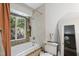 Bright bathroom with tub and shower, tiled walls and trim, and window overlooking trees at 5604 Hideaway Dr, Chapel Hill, NC 27516