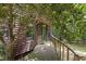 Exterior view of a cozy cabin with a wooden ramp and green front door, surrounded by trees at 5604 Hideaway Dr, Chapel Hill, NC 27516