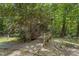 Exterior of home with accessible ramp, siding, lush greenery, flowering bushes and surrounding forest at 5604 Hideaway Dr, Chapel Hill, NC 27516