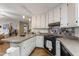 Open kitchen with light colored cabinets, modern fixtures, breakfast bar, wood floors and tile backsplash at 5604 Hideaway Dr, Chapel Hill, NC 27516
