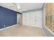 Bright bedroom featuring neutral carpeting, double closets, and large window at 5804 Heatherbrook Cir, Raleigh, NC 27612