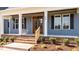 Close-up of a welcoming front porch with a wooden door, white columns, and neatly trimmed shrubs at 60 Stream View Way, Spring Hope, NC 27882