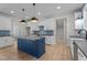 Bright kitchen featuring white cabinets, a navy blue island, modern lighting, and stainless steel appliances at 60 Stream View Way, Spring Hope, NC 27882