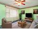 Cozy living room featuring bright green walls, a ceiling fan, and plush seating for a comfortable and inviting atmosphere at 605 Mace Rd, Mebane, NC 27302