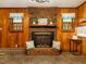 Charming living room showcasing a brick fireplace, warm wood paneling, and decorative accents that evoke comfort at 605 Mace Rd, Mebane, NC 27302
