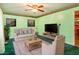 Inviting living room with light green walls, plush seating, a ceiling fan, and natural light creating a relaxing atmosphere at 605 Mace Rd, Mebane, NC 27302
