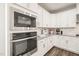 Modern kitchen showcasing built-in stainless steel microwave and oven, complemented by sleek white cabinetry and granite countertops at 672 Millers Mark Ave, Wake Forest, NC 27587