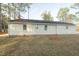 A view of the home's backyard featuring mature trees and brick foundation at 75 Hartwell Cir, Lillington, NC 27546