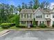 View of townhome featuring green siding, stone accents, manicured landscaping, and convenient parking at 7871 Allscott Way, Raleigh, NC 27612