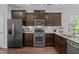 Stylish kitchen with stainless steel appliances, granite countertops, and dark wood cabinetry at 7871 Allscott Way, Raleigh, NC 27612