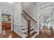 Well-lit staircase featuring wood steps and white banisters, adjoining a kitchen and living room at 7929 Pine Timber Dr, Raleigh, NC 27613