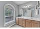 Bright bathroom featuring a large window, a white countertop and brown cabinets at 8504 Delavan Cir, Raleigh, NC 27613