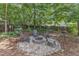 Cozy backyard fire pit with stone surround and seating, nestled under mature trees at 8504 Delavan Cir, Raleigh, NC 27613