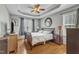 Spacious main bedroom with a tray ceiling, ceiling fan, hardwood floors, and natural light at 8504 Delavan Cir, Raleigh, NC 27613