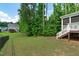 Green backyard with lush lawn, mature trees, and a partial view of the screened-in porch at 851 Dotson Way, Apex, NC 27523