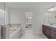Inviting bathroom with a soaking tub, tile surround, and an open doorway to closet at 851 Dotson Way, Apex, NC 27523