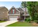 Charming two-story home featuring a stone facade, two-car garage, and a welcoming front porch, surrounded by lush greenery at 851 Dotson Way, Apex, NC 27523