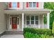Inviting front porch with red door, white railing and meticulously maintained landscaping welcomes you home at 851 Dotson Way, Apex, NC 27523