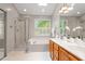 Bright bathroom featuring a glass-enclosed shower, soaking tub, and double vanity with abundant natural light at 9400 Leslieshire Dr, Raleigh, NC 27615