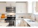 Close-up of kitchen with stainless steel appliances, white cabinets, subway tile backsplash, and granite counters at 9400 Leslieshire Dr, Raleigh, NC 27615