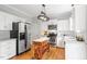 Modern white kitchen with stainless steel appliances, island, and hardwood floors, offering ample counter space at 9400 Leslieshire Dr, Raleigh, NC 27615