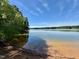 Beautiful lake view with sandy shoreline and clear water under a bright, sunny sky at 96 Holly Cir, Henderson, NC 27537