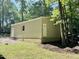 Outbuilding with an additional door on a property surrounded by trees and a lush lawn at 96 Holly Cir, Henderson, NC 27537