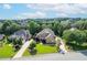 Aerial view showcases a well-maintained brick home nestled among lush trees in a desirable neighborhood with manicured lawns at 1010 Mill Pointe Way, Elon, NC 27244