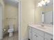 Bright bathroom with a toilet, sink and vanity with white cabinets and a mirror at 1010 Mill Pointe Way, Elon, NC 27244