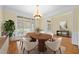 Formal dining room with wood table, six chairs, elegant chandelier, large windows and adjacent decorative plant at 1010 Mill Pointe Way, Elon, NC 27244