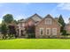 Imposing two-story brick home featuring manicured lawn, mature trees, and a well-maintained landscape at 1010 Mill Pointe Way, Elon, NC 27244