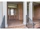 Welcoming front porch with brick columns, decorative glass door and black metal railings at 1010 Mill Pointe Way, Elon, NC 27244