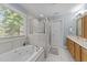 Bright bathroom featuring a soaking tub, glass shower, and double sink vanity with modern fixtures at 104 Kylesku Ct, Apex, NC 27502