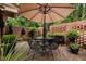 Brick patio with outdoor table and chair set under an umbrella, surrounded by lush plants at 1112 Blenheim Dr, Raleigh, NC 27612