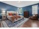 Bedroom featuring a bed with orange accents, blue walls, wood floors, and natural light at 1148 Tringham Ct, Apex, NC 27502