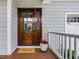 Elegant wood front door with glass panels, decorative plants, and a welcoming doormat at 1148 Tringham Ct, Apex, NC 27502