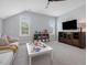 Bright playroom with white couch, TV, and ceiling fan at 1148 Tringham Ct, Apex, NC 27502