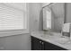 Charming bathroom featuring a dark vanity, white countertop, window and large framed mirror at 117 Banning Dr, Pittsboro, NC 27312