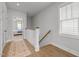 Hallway featuring wood floors, white trim, and a glimpse into a bedroom; natural light from window at 117 Banning Dr, Pittsboro, NC 27312