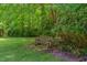Secluded backyard with mature trees, flowering bushes, and a inviting wooden bench on a lush lawn at 117 Carolina Forest Rd, Chapel Hill, NC 27516
