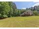 Spacious backyard view featuring manicured lawn with mature trees and back of two-story home at 117 Carolina Forest Rd, Chapel Hill, NC 27516
