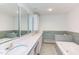 Bathroom featuring double sinks with vanity, large mirrors, white cabinets and separate bathtub at 117 Carolina Forest Rd, Chapel Hill, NC 27516