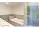 Bathroom showcasing a large bathtub next to a clear glass shower, white countertop and neutral tile surround at 117 Carolina Forest Rd, Chapel Hill, NC 27516