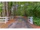 Long, winding driveway through lush woods with white fencing at the entrance at 117 Carolina Forest Rd, Chapel Hill, NC 27516