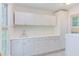 Well-lit laundry room with white cabinetry, countertop space, and a sink at 117 Carolina Forest Rd, Chapel Hill, NC 27516