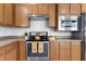 Close up of kitchen with stainless steel appliances, wood cabinets, and laminate floors for a modern and functional space at 118 Rosedale Creek Dr, Durham, NC 27703