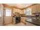 Bright kitchen featuring neutral cabinetry, sink beneath window, and tiled floors at 133 Parkhaven Ln, Garner, NC 27529